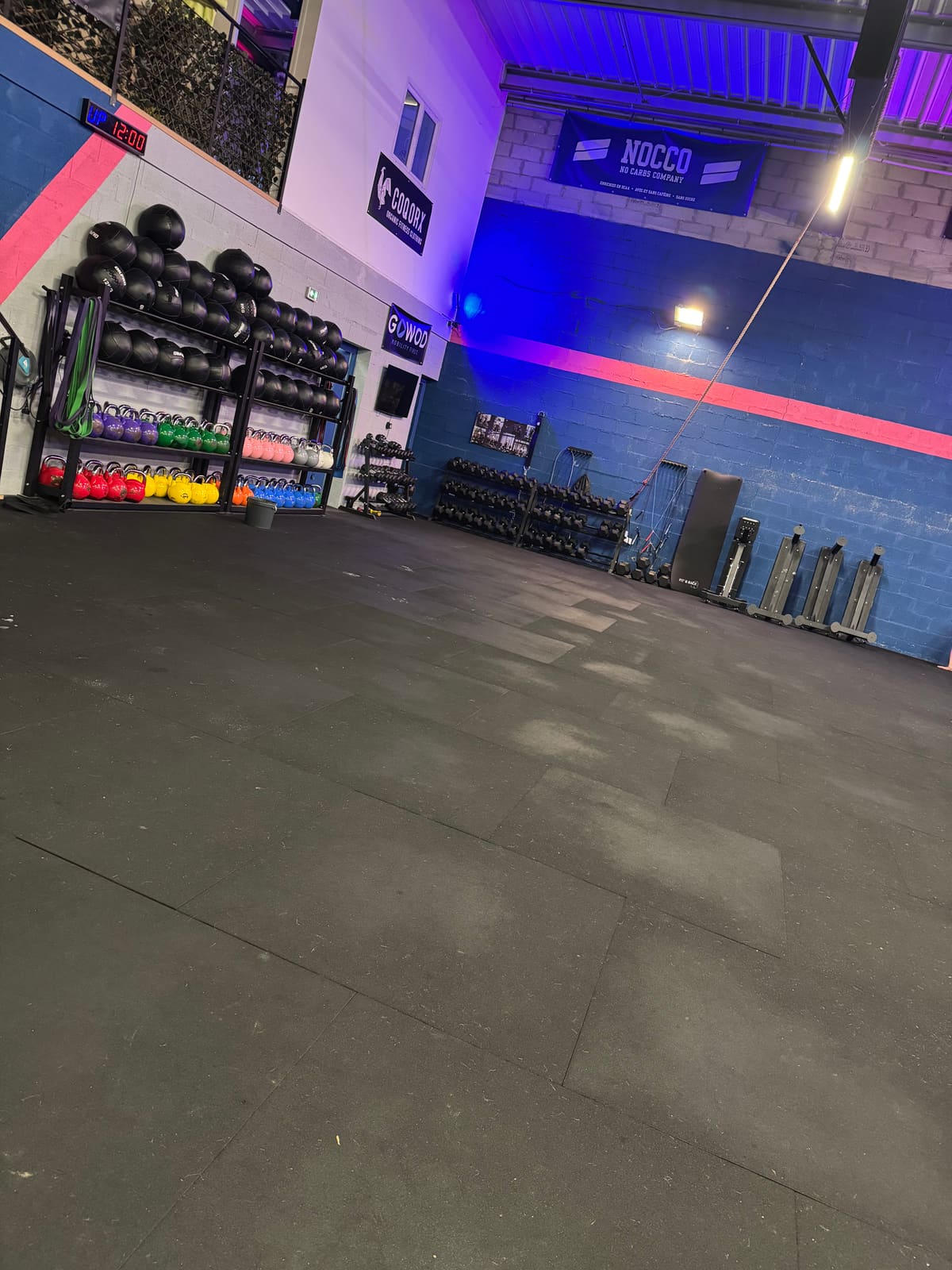 Vue d'ensemble de la salle de CrossFit : rig, disques colorés et sol sombre